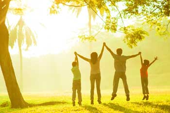 Eine Gruppe Kinder springen händehaltend im Sonnenschein